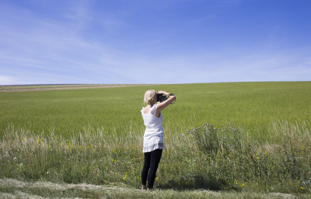 身着白衣的妇女在拍摄一片生机勃勃的绿色牧场图片下载