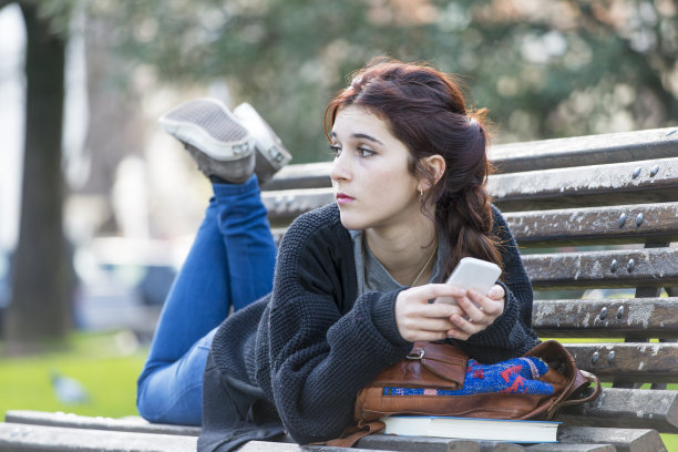 沉思的美丽女孩躺在长椅上，青春期的生活理念。图片下载