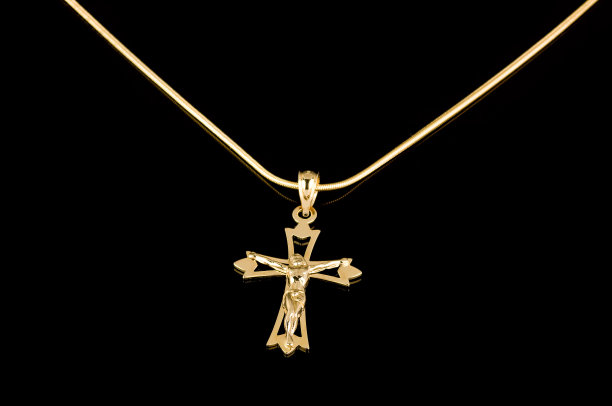 十字形状的黄金吊坠在黑色反光的背景图片下载