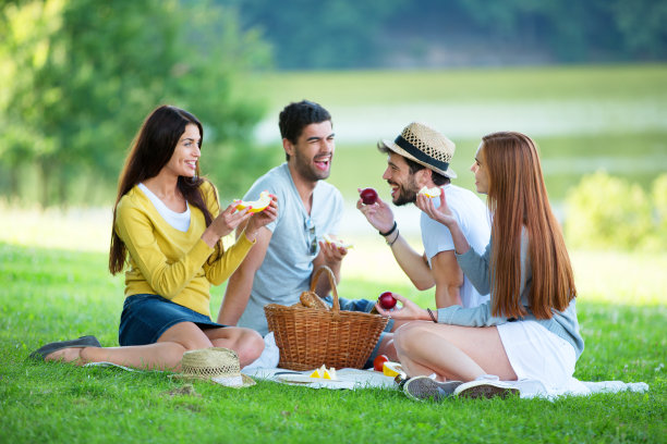 一群朋友在绿色草地上野餐图片下载