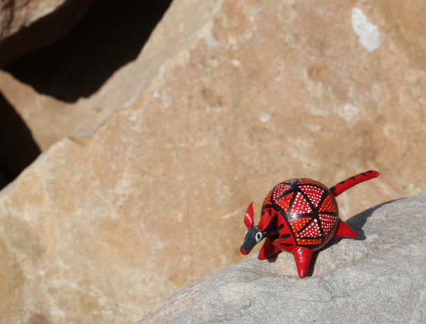 棕色岩石上的红色木制玩具犰狳图片下载