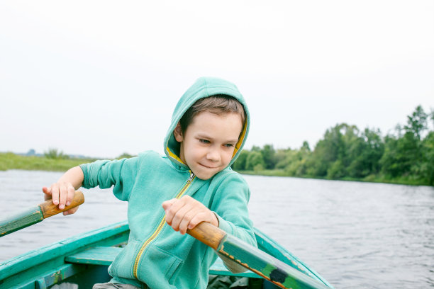 一个男孩在河中央划船图片下载