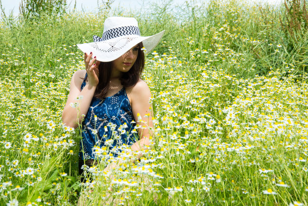年轻女子在草地上的花朵。图片下载