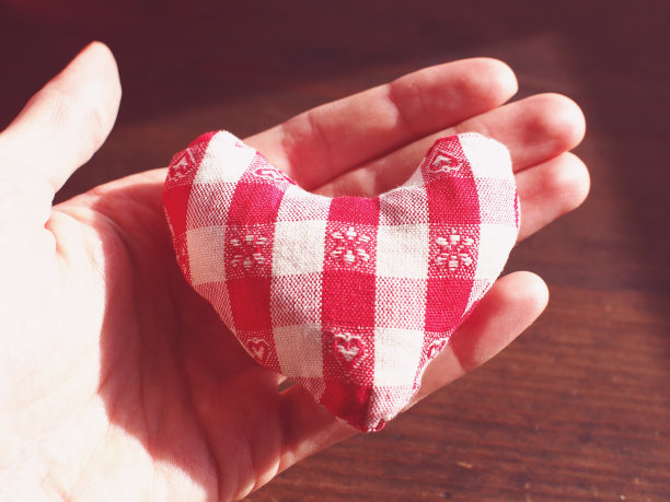 画布小柔软的心在开放的手在木制的背景图片下载