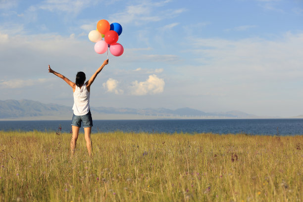 在草地上用彩色气球为年轻的亚洲妇女欢呼图片下载