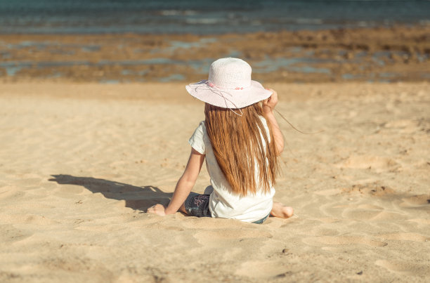 沙滩上戴着帽子的小女孩图片下载