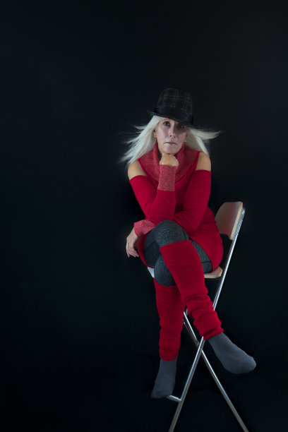 成熟的女人侧坐在白色的椅子上图片下载