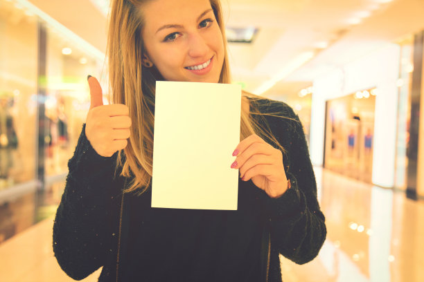有魅力的女人在商场拿着一本书。图片下载