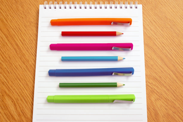 彩色笔放在桌上的记事本上图片下载