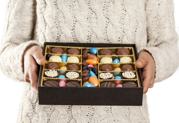 女人用手提供盒子里的巧克力图片下载
