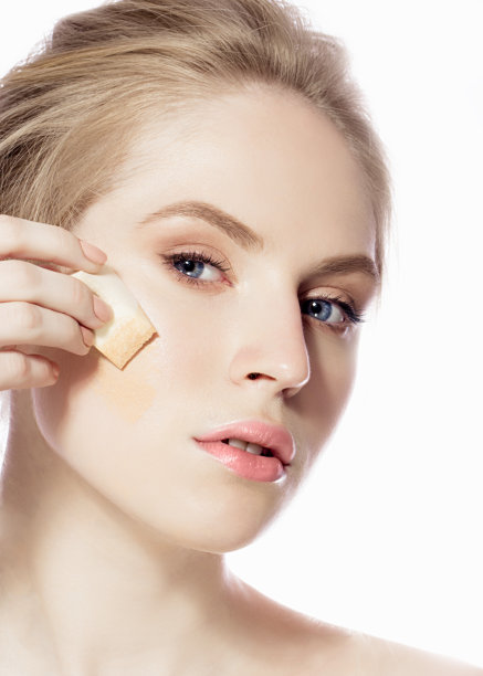 用海绵在脸上敷粉底的女人图片下载