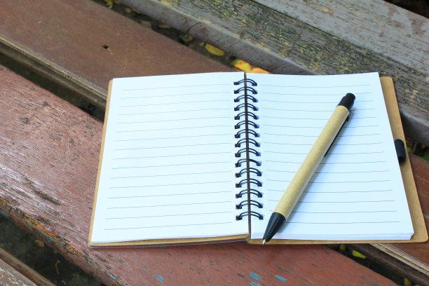 笔记本和笔放在棕色的长凳上图片下载