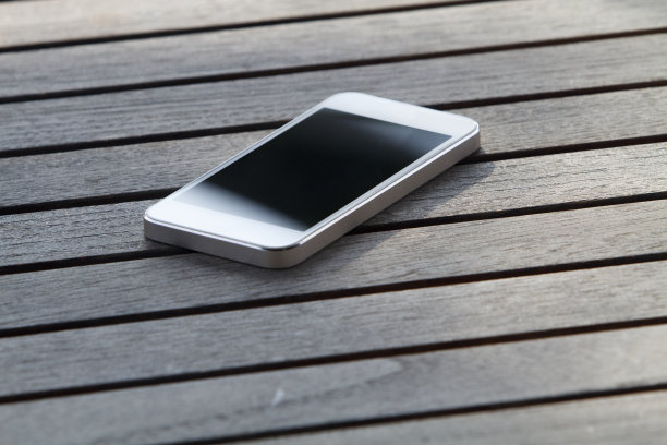 木桌上放着白色的智能手机图片下载