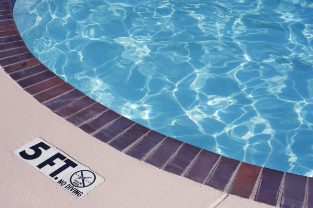 闪闪发光的蓝色游泳池边缘与梯子图片下载