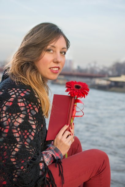 黑发女孩拿着一本书在河边图片下载