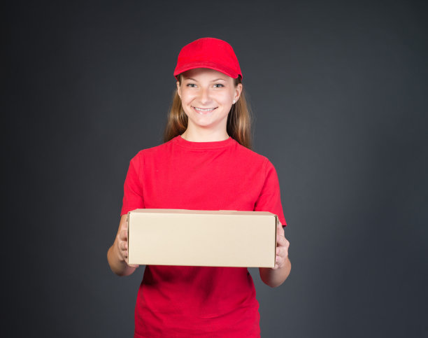 快递员在送包裹的时候微笑着，穿着红色的制服。图片下载