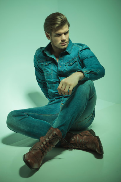 时尚男士手放在膝盖上坐着。图片下载