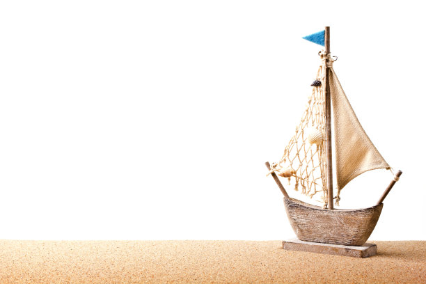 把玩具船模型放在沙滩上的沙子里图片下载