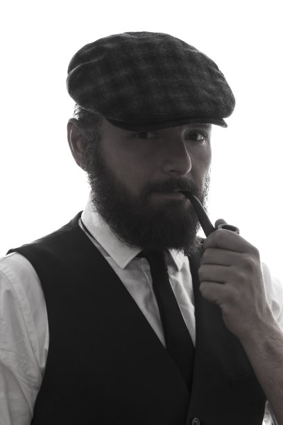 优雅的大胡子男子吸烟斗肖像图片下载