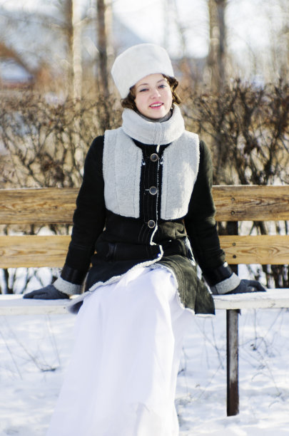 在冬日公园的长椅上微笑的女孩图片下载