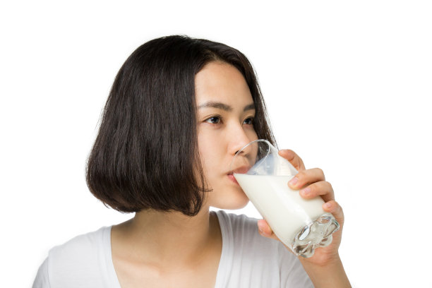 可爱健康的女人正在喝玻璃杯里的牛奶。图片下载