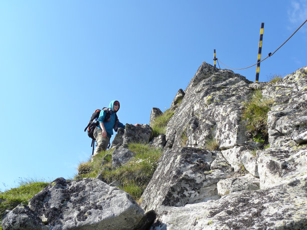 年轻的女孩站在岩石嶙峋的山坡上图片下载