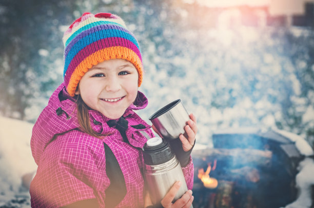 笑着喝茶的小女孩的冬天肖像图片下载