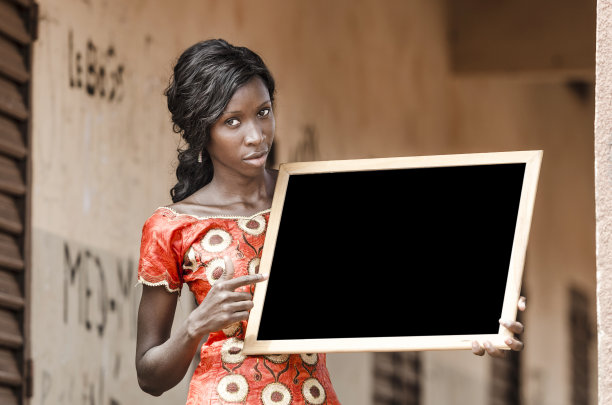 美丽的非洲民族大学女孩拿着并指着黑板图片下载