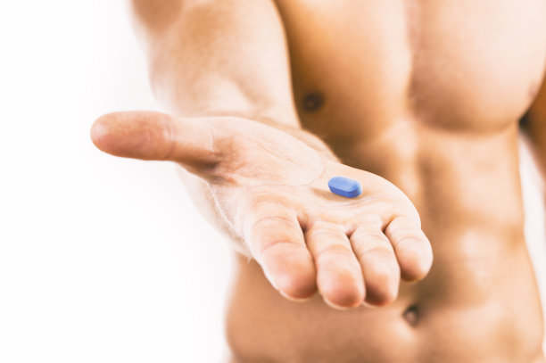 肌肉发达的年轻人拿着蓝色药丸图片下载