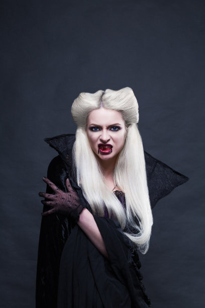 美丽的金发女孩吸血鬼站。图片下载