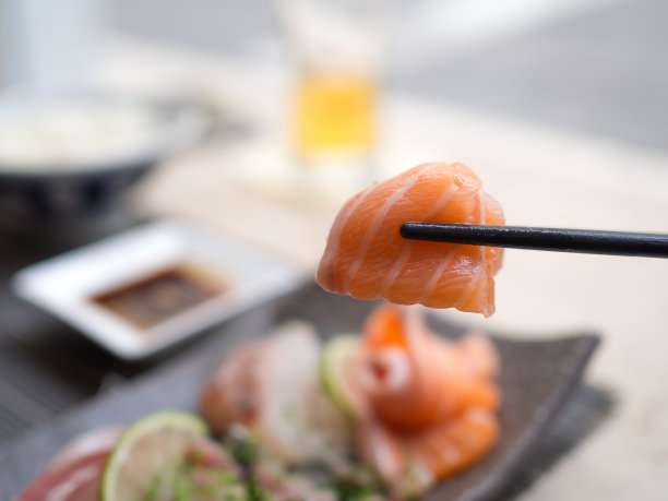 美味的三文鱼刺身夹在筷子上。图片下载