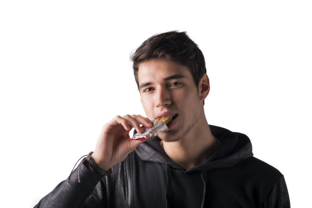 英俊的年轻人吃着麦片棒，孤立无援图片下载