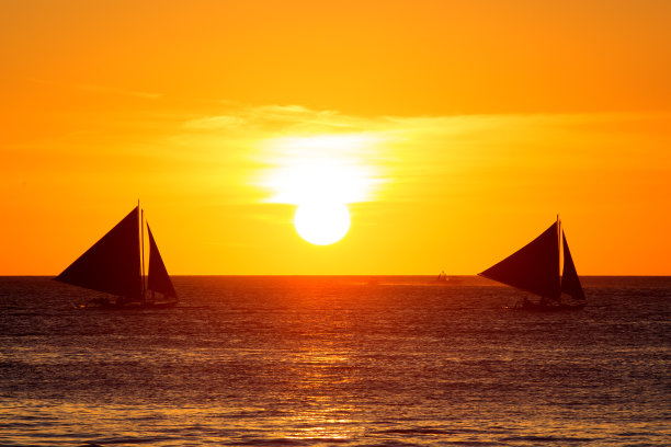 热带海上日落时的帆船。剪影照片。图片下载