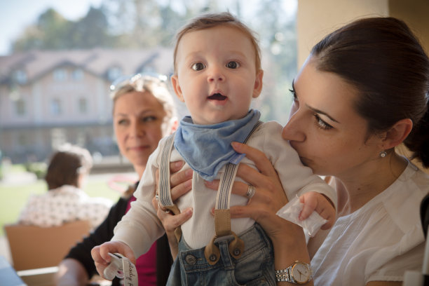 年轻的母亲抱着她的孩子。妈妈和她的朋友在喝咖啡。图片下载