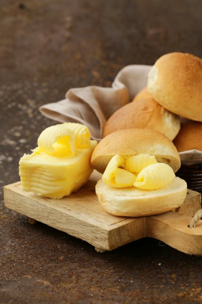 新鲜的小圆面包上涂着黄色的牛奶黄油作为早餐图片下载