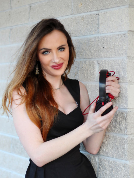 穿着黑色连衣裙，手拿耳机的迷人女孩图片下载