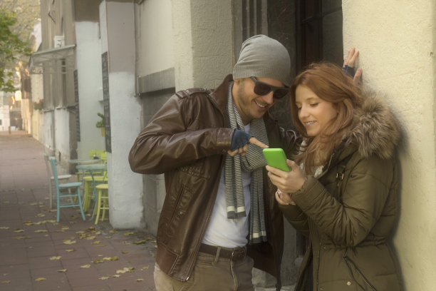 情侣在户外用手机相爱。图片下载