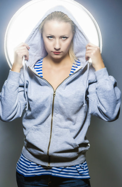 金发白种人女性在帽衫站在演播室的环境图片下载