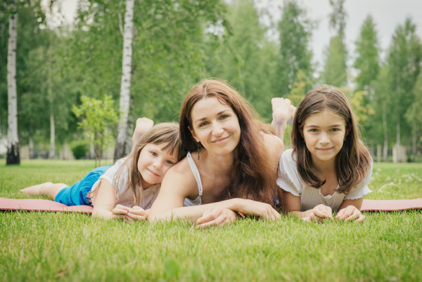 母亲和两个年幼的女儿在草地上休息图片下载