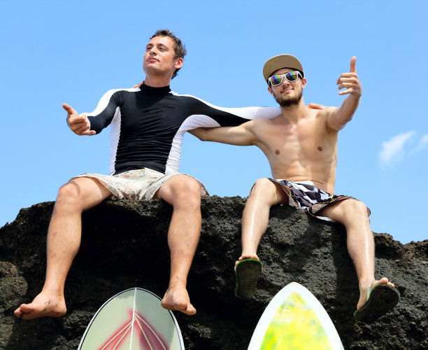 两个冲浪朋友坐在一块岩石上图片下载