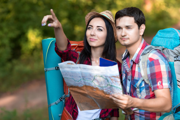 年轻女子和男子与背包旅行服装持有地图图片下载