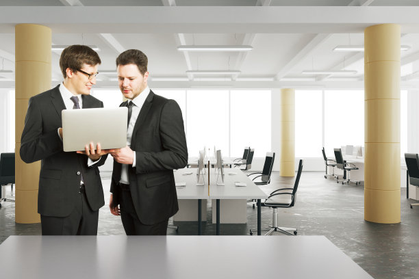 商人在现代阁楼风格的办公室里看笔记本电脑图片下载