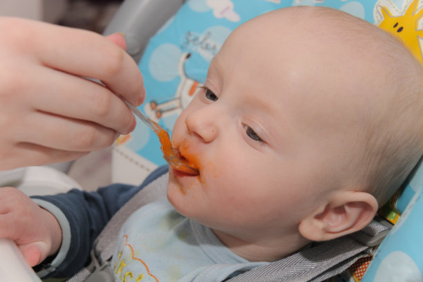 年轻的母亲在家里喂养儿子素材图片