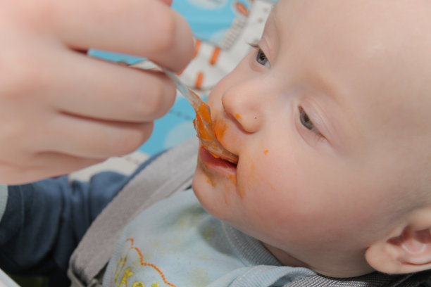 年轻的母亲在家里喂养儿子素材图片