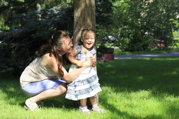 快乐的母亲和年幼的女儿在城市公园玩。图片下载