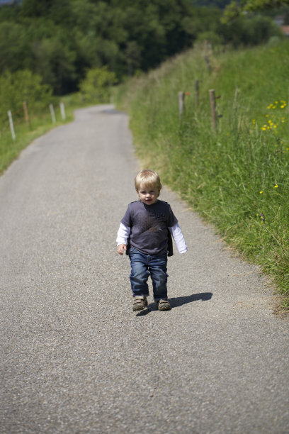 蹒跚学步的孩子走在路上。图片下载