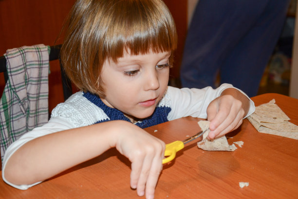快乐的小女孩在家里用剪刀图片下载