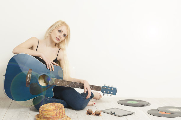 女音乐家坐在地板上，拿着原声吉他图片下载