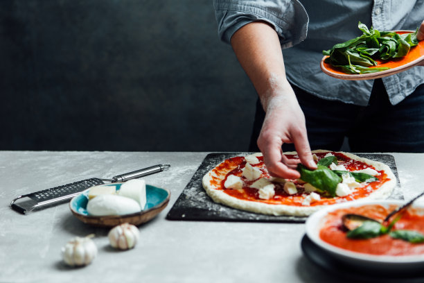 男人在披萨上撒罗勒叶图片下载