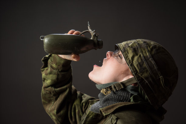 口渴的士兵喝着最后的水滴，穿着绿色迷彩服戴着头盔的女兵图片下载